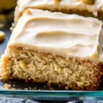 Homemade banana cake with rich cream cheese frosting, highlighting its moist texture and golden edges.